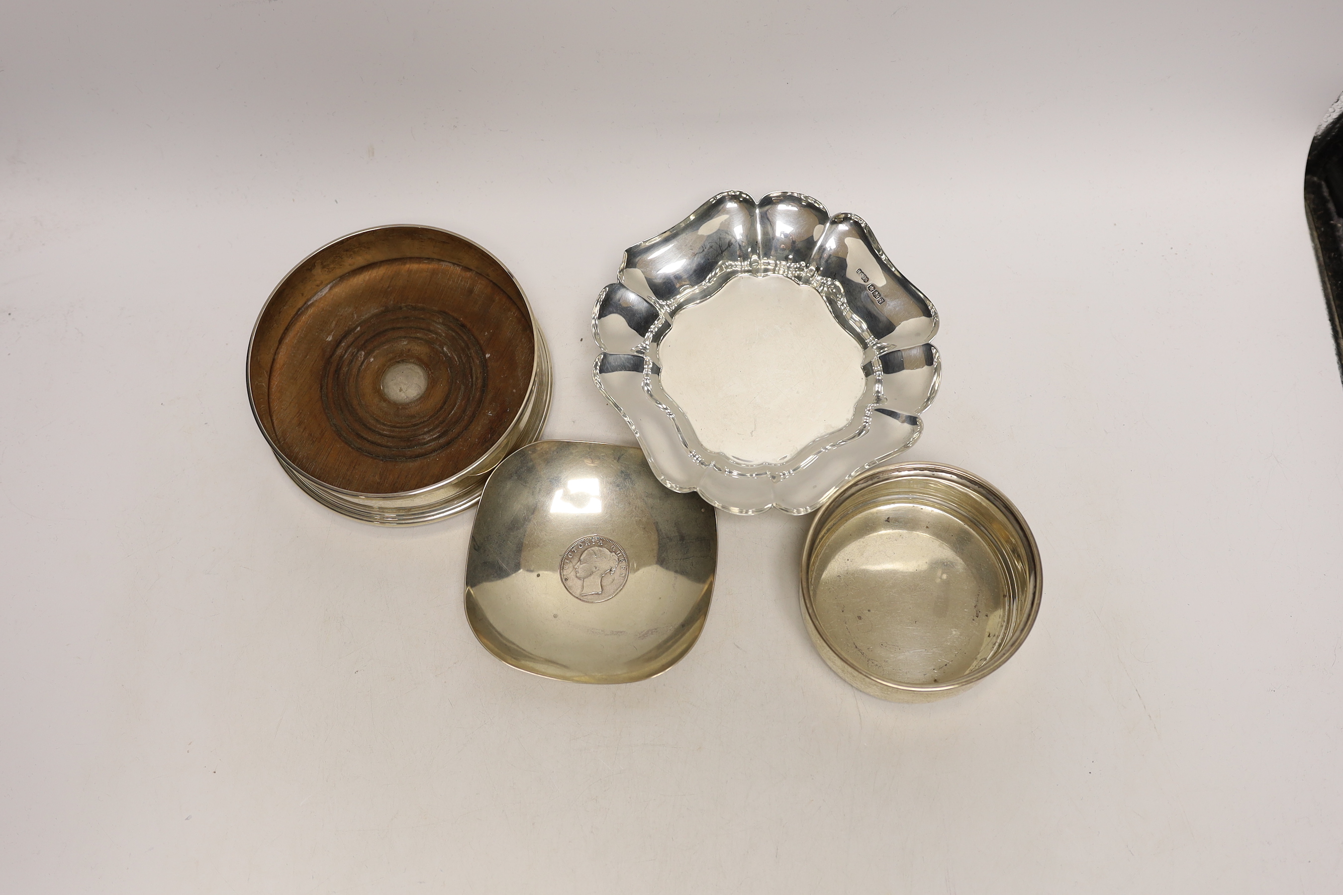 A small George V silver bowl, Sheffield, 1934, a silver bottle coaster, a small Indian white metal dish with inset rupee coin and a further small silver christening bowl.